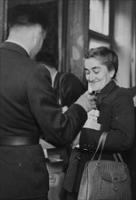 A nurse receiving her emergency ration: chocolate, Ovomaltine, tinned food, soup cubes, crispbread