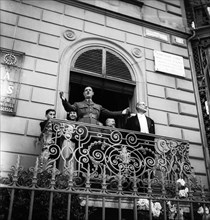 General Charles de Gaulle on a balcony waving to the crowd in Geneva, 1946 .