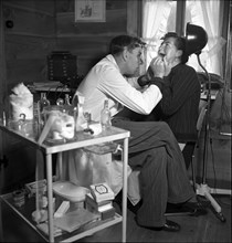 Dentist with patient, in the 40s .