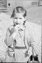 Girl eating chocolate; around 1943.