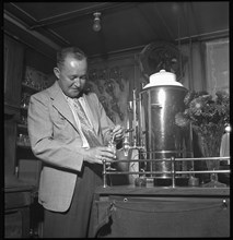 Heinz Ambuehl serving schnapps at his restaurant; Zell ca. 1948 .