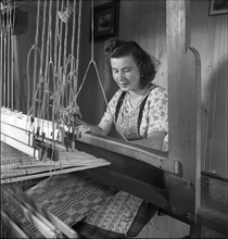 Young woman weaving bast fibre by hand loom, 1946 .