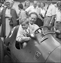 Emmanuel de Graffenried and son in racing car, 1950