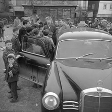 Children crowding around Martin Schaffner with Mercedes Benz, Rorschach 1958