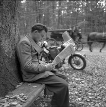 Man reading the newspaper in the forest, around 1960