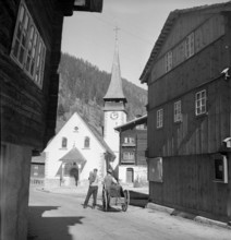 Men with handcart in front of the church; Biel VS; 1946.