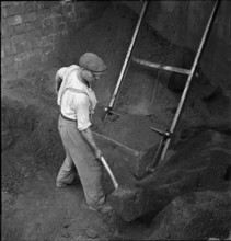 Worker shoveling coal; production of briquettes; 1943.