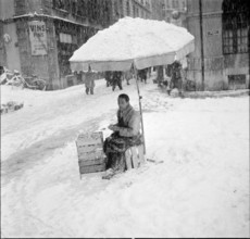 Snowfall in Lausanne: vendor offering potatoes for sale; 1952.