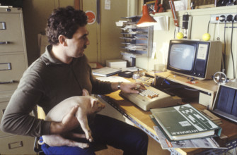 Computers and agronomy: farmer with a young swine, 1984.