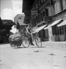 Boy on bike pulling a wooden handcart, 1940.