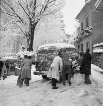 Snowfall in Lausanne: men bump-starting a car; 1952.