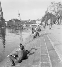 People strolling along the Limmat river.