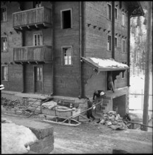 Herbriggen, village threatened with landslide, evacuation, men loading goods on sledge; 1959