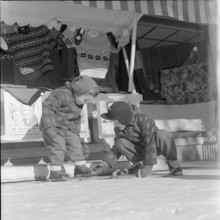 Steering; boy helping girl to put on her skis; 1957