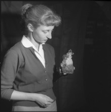 Woman looking at cross-shaped rock crystal; 1959