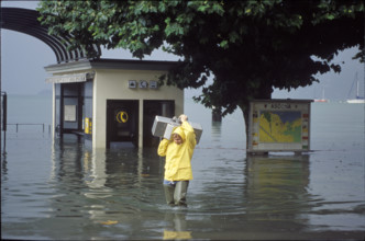 Man carrying a coin-box telephone, flood in Ascona 1993