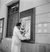 Davos: Man hangs up a poster of the tourist association; 1949