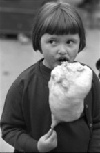 Girl eating cotton candy at fair in Wohlen AG, 1965