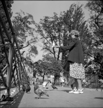 Geneva: Ile Rousseau, woman feeding pigeons; 1946