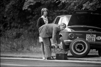 Man helping woman driver after puncture, 1974