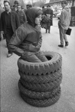 Thun, sale of used army equipment, young man with car tires; 1969