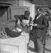 Woman examining scraps of fabric for rag rugs, 1940