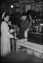 Saleswoman serves customers in a grocery store; 1945