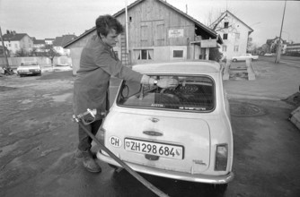 Zurich, gas station attendant cleans rear window; 1970