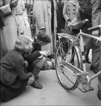 Children examine bicycle tires reinforced with aluminum; 1942