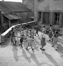 Coinsins; Teacher Elisabeth Glauser and her class playing ringaringaroses; 1949