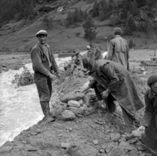 Täsch. men building up an embankment with stones. 1957