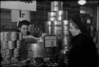 Salesperson serving customer in a food shop. soup on offer. 1945