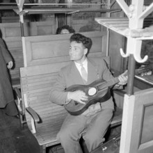 Railway journey through the Gotthard tunnel: passenger playing the guitar, 1957.