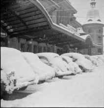 Snowfall in Lausanne: snowy cars in front of the railway station; 1952.