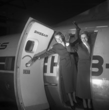 Swissair hostesses waving out of airplane door 1953.