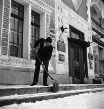 Davos, man shoveling snow in front of hotel; 1949.