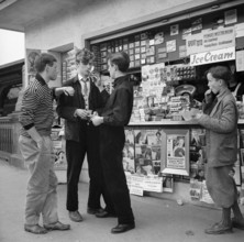 Teenagers, adolescent boys smoking in front of a kiosk; Zurich 1956.