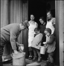 Milk man serving a family; customer; 1941.