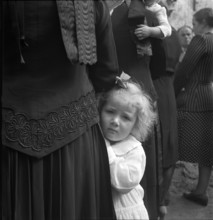 Little girl hanging on to her mother, 1942.