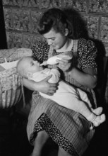 WW2 : farming camp; young woman feeding infant, 1941.