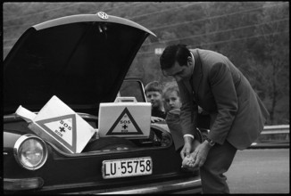 Man cares for foot injury with first aid case in his car 1970.