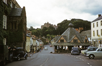 Dunster castle and Yarn Market building, main village street, High Street, Dunster, Somerset,