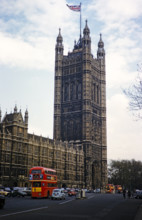 Red double-decker buses passing Westminster Abbey church,  London, England, UK 1962.
