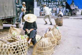Woman selling chickens in baskets at street market, Tai Po, New Territories, Hong Kong, Asia, 1964.