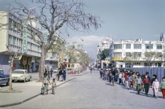 Primary school children walking hand in hand along city centre commercial street, Macau, Asia 1964.