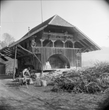 Man bundling firewood in front of a granary in Wynigen BE 1960