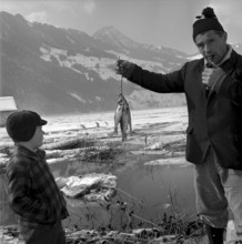A fisherman showing fish to a boy, Seewen SZ 1965