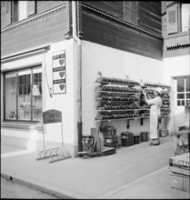 Baker puts loafs of bread on shelves outside the bakery, Brienz 1944