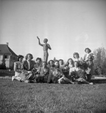 Women posing around the sculpture of a nude youth 1947