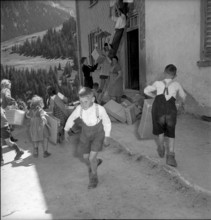 Children carrying parcels, relief supplies for the population of the completely burned down hamlet
